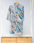 Display of white, black, orange, blue, aqua and brown abstract print dress