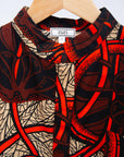 Display of beige shirt with brown and orange circles and lines.