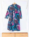 Display of black dress with colorful peacock feather print..