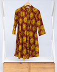 Display of red dress with yellow and brown flowers.