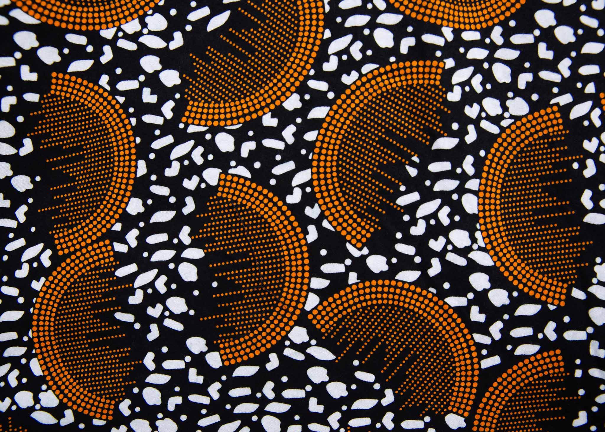 Close up Display of black and white dress with orange half circle print, fabric.