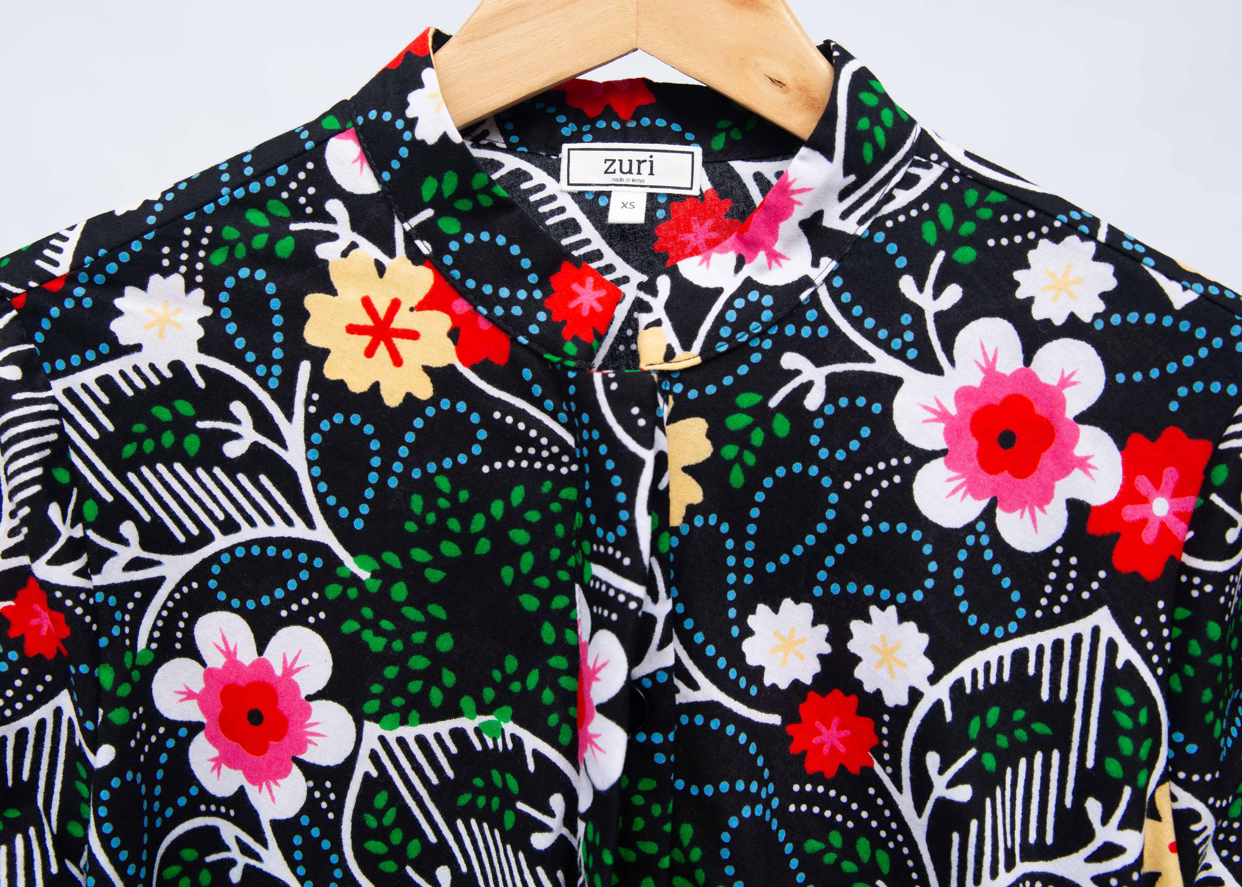 Display of black dress with white, green, red and yellow floral print.
