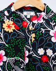Display of black dress with white, green, red and yellow floral print.