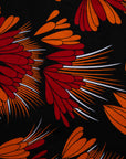 Close up Display of black dress with orange, red and white floral print, fabric.