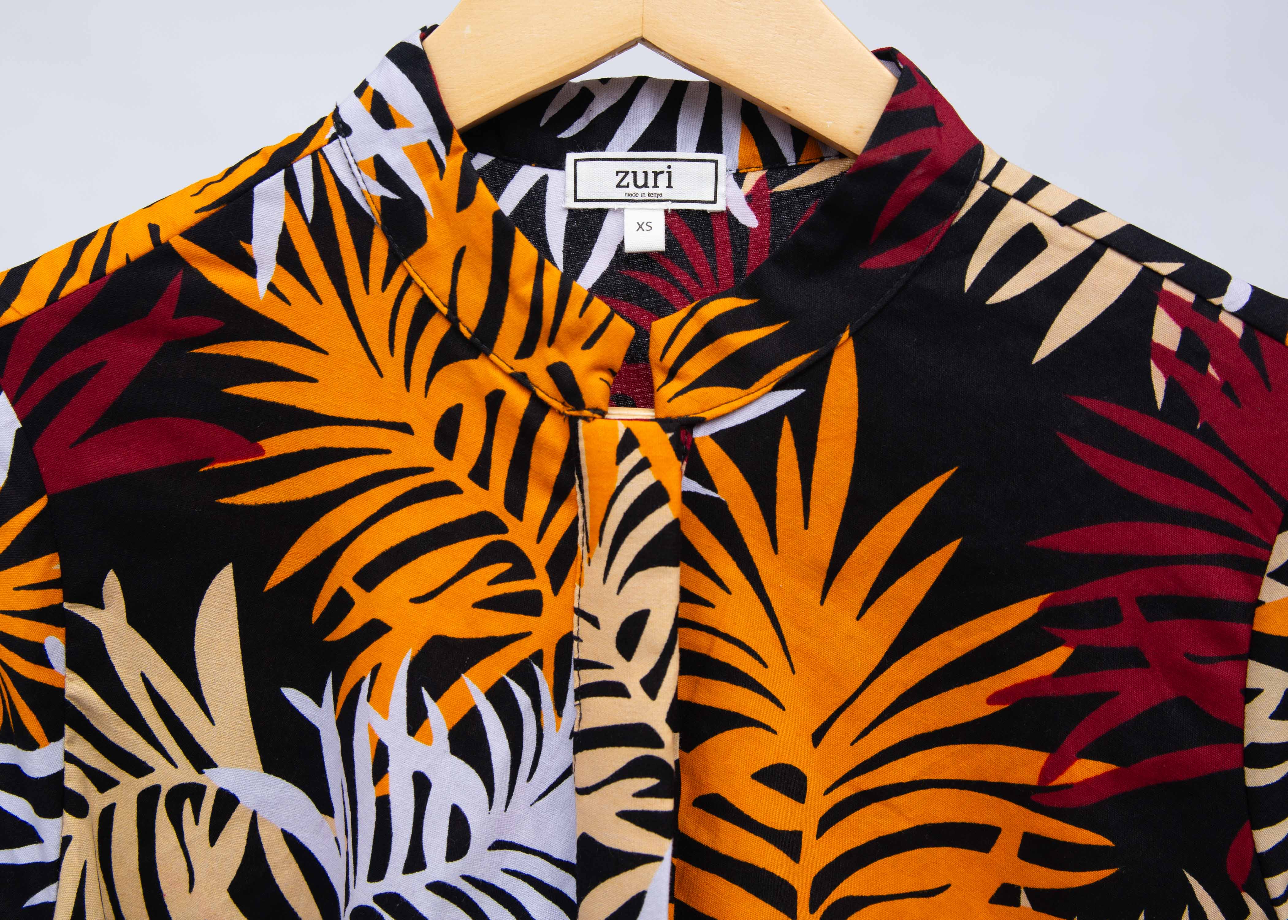 Display of black dress with orange, red and white leaf print.