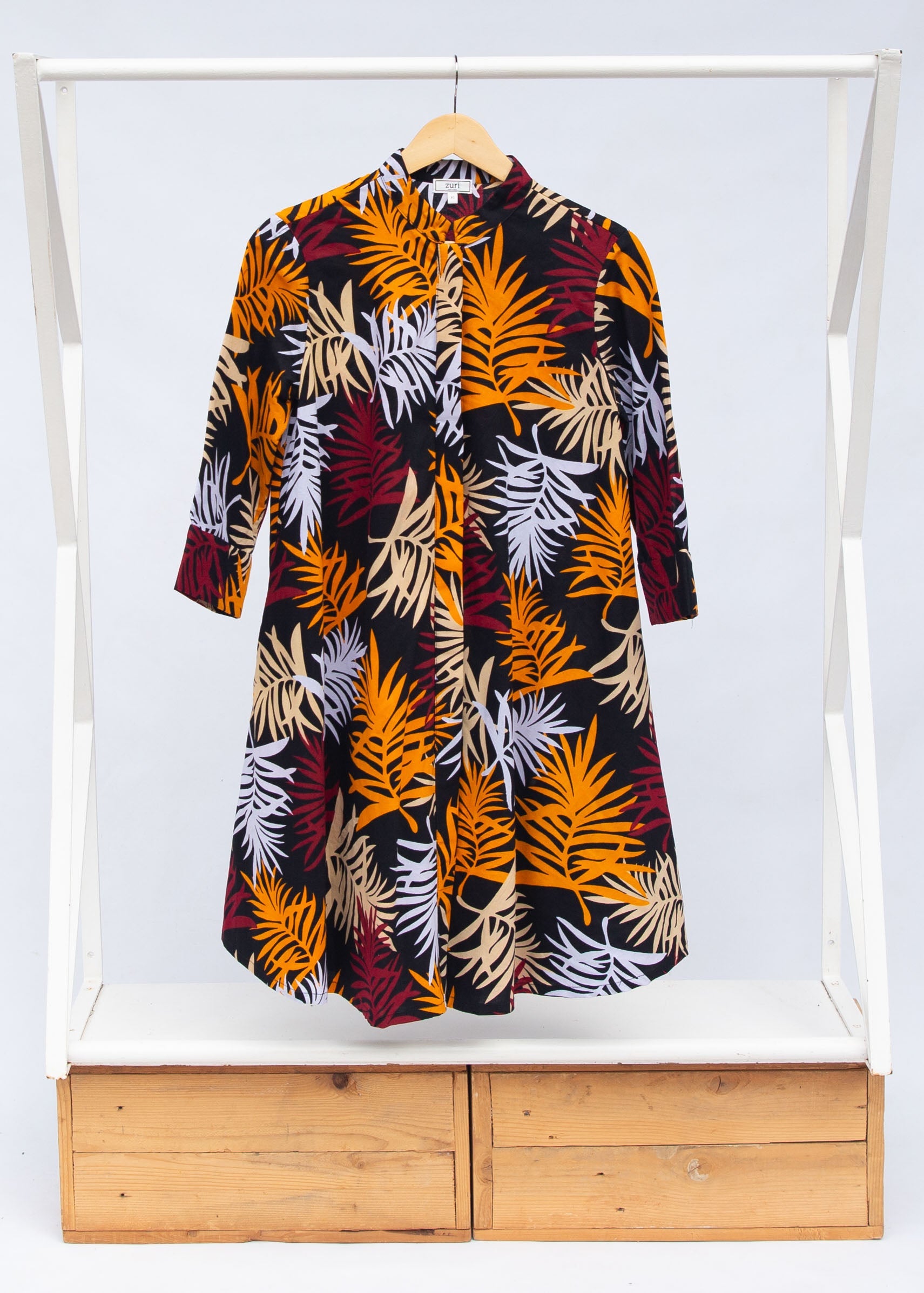 Display of black dress with orange, red and white leaf print.