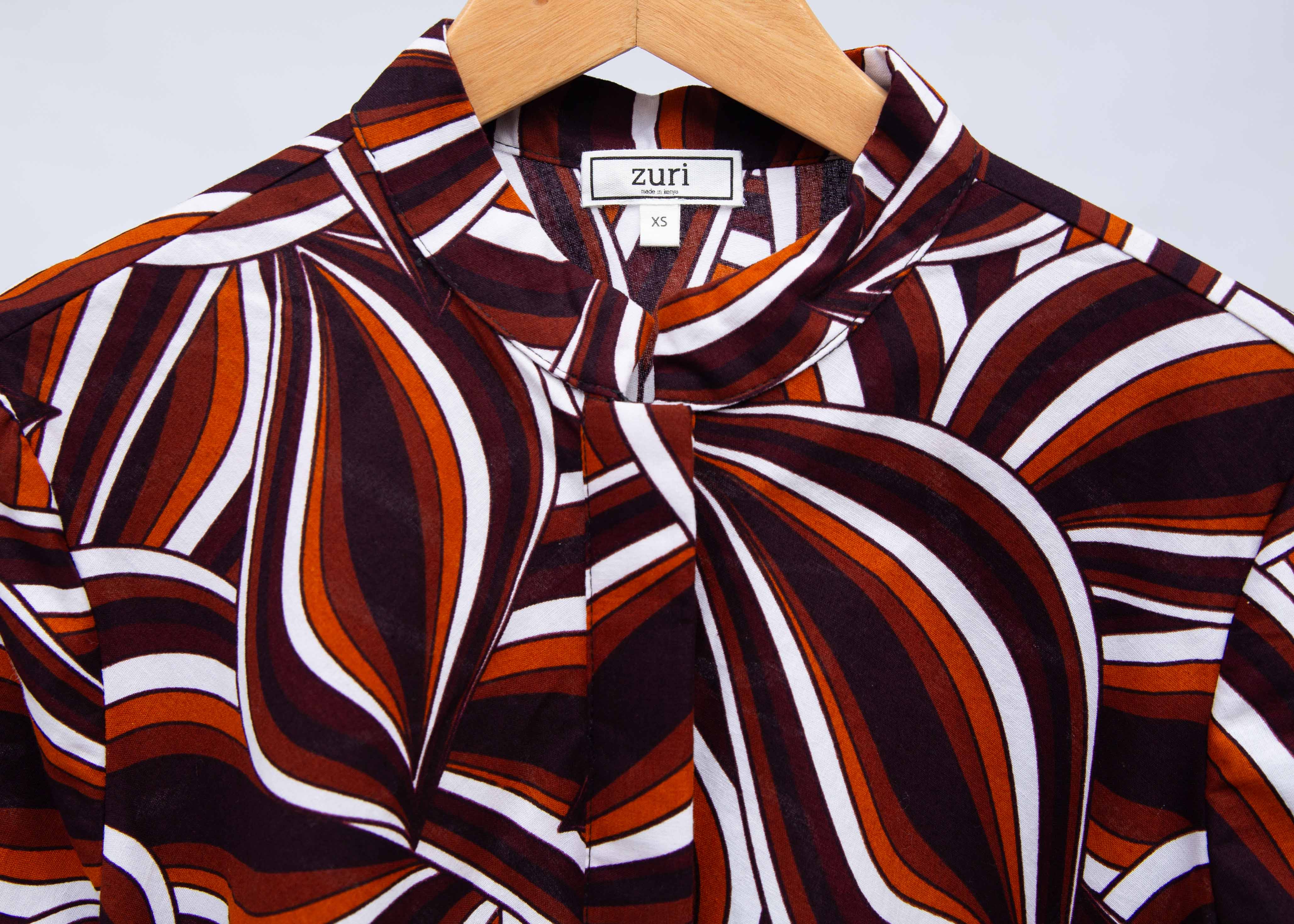 Display of brown, orange, burgundy and white abstract print dress.