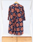 Display of navy dress with brown flowers and white swirls.