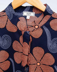 Display of navy dress with brown flowers and white swirls.