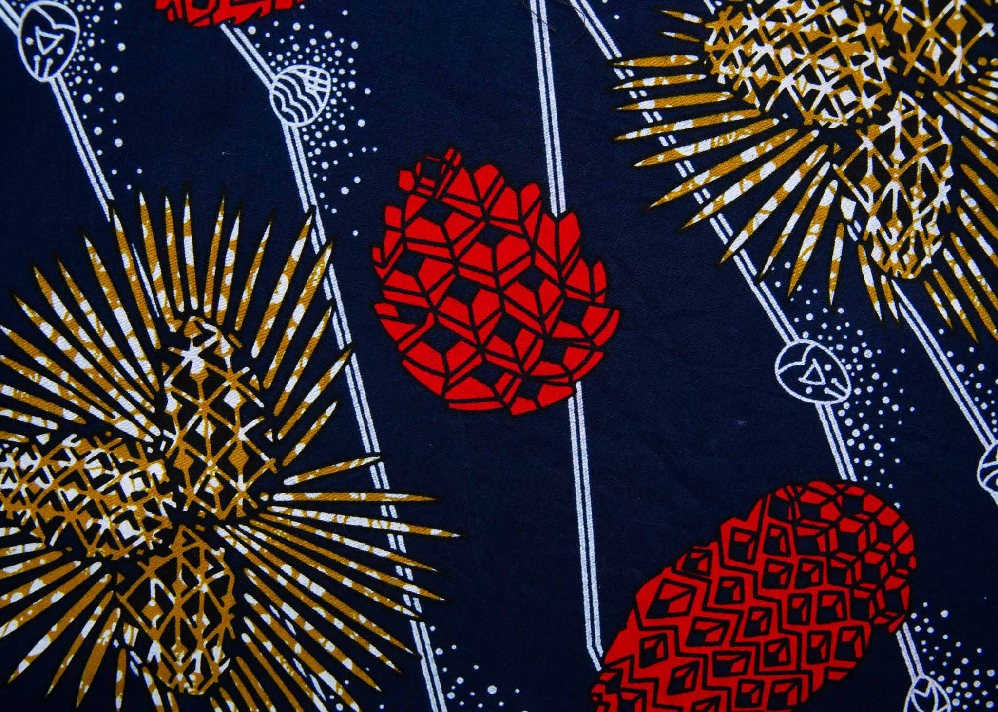 Close up display of navy sleeveless dress with red, yellow and white splatter print, fabric.