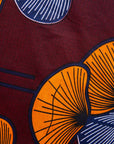Close up display of burgundy sleeveless dress with yellow and white flowers, fabric.