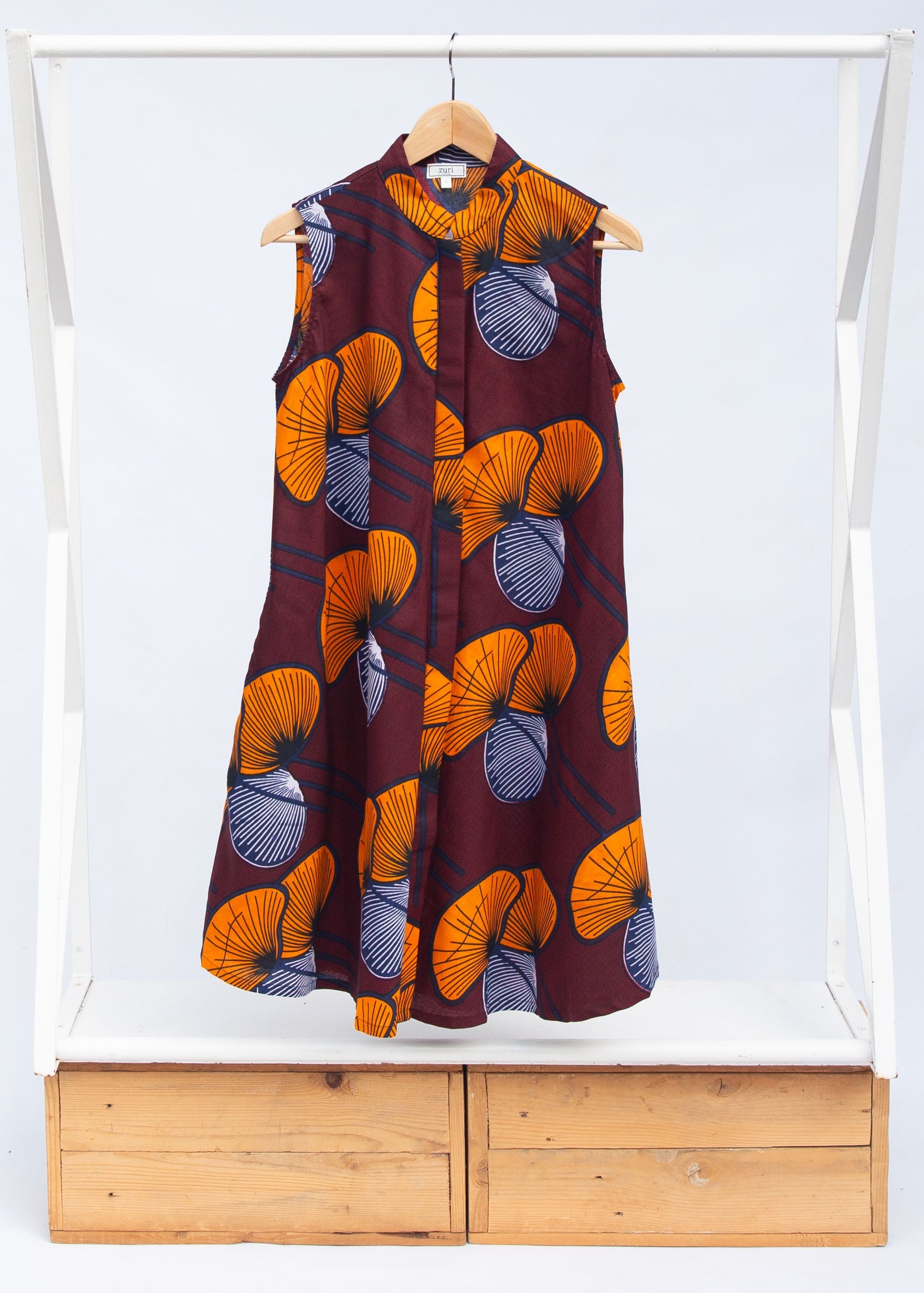 Display of burgundy sleeveless dress with yellow and white flowers.