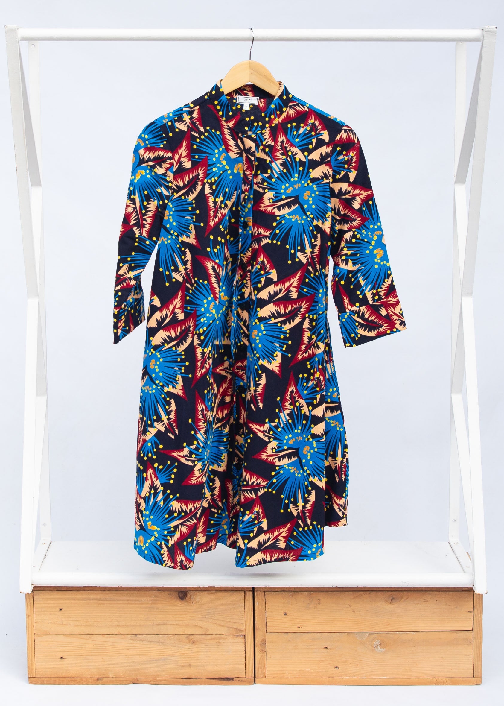 Display of black dress with blue, beige and red splatter print.