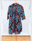 Display of black dress with blue, beige and red splatter print.