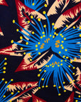 Close up display of black dress with blue, beige and red splatter print, fabric.