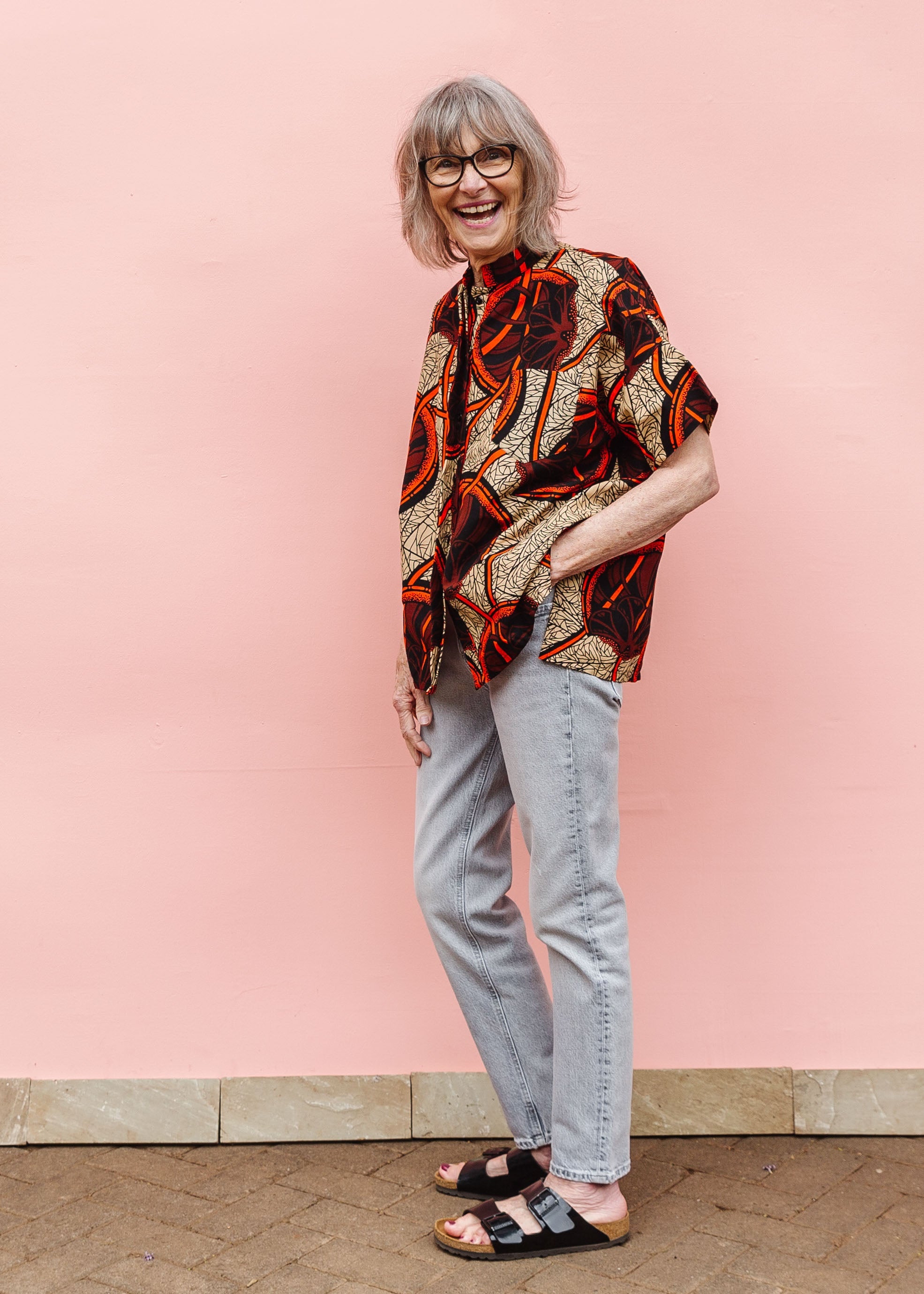 Model wearing beige shirt with brown and orange circles and lines.