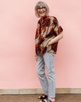 Model wearing beige shirt with brown and orange circles and lines.