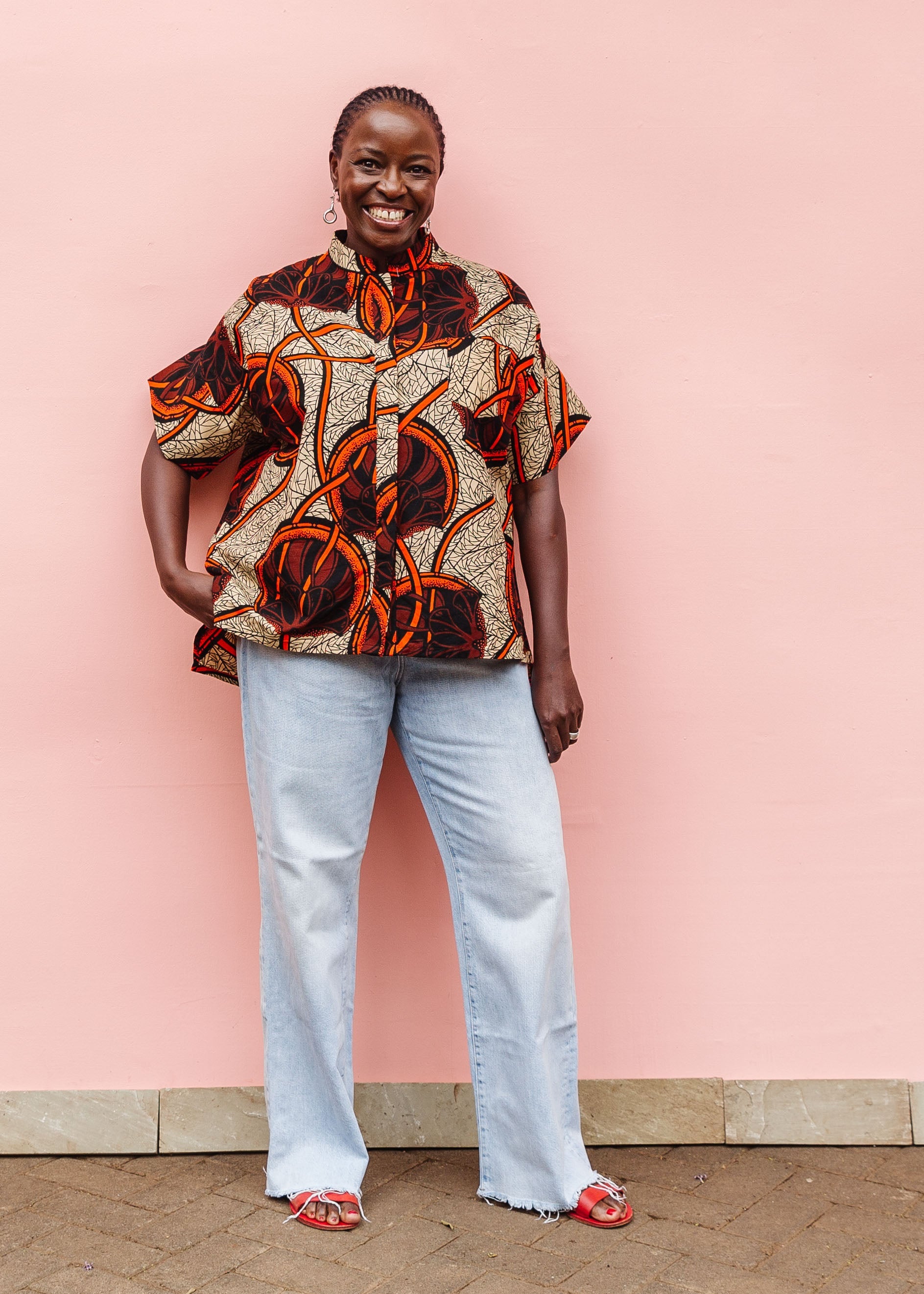 Model wearing beige shirt with brown and orange circles and lines.
