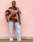 Model wearing beige shirt with brown and orange circles and lines.