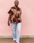 Model wearing beige shirt with brown and orange circles and lines.