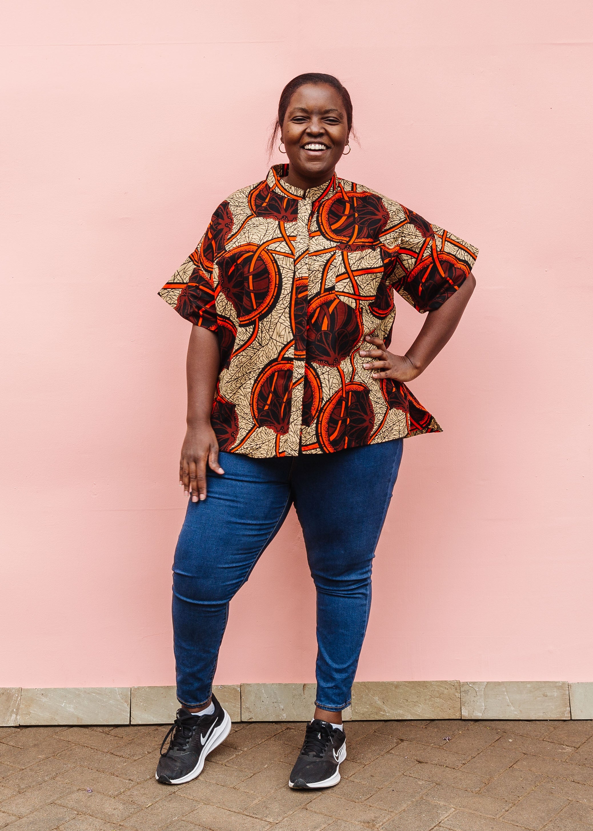 Model wearing beige shirt with brown and orange circles and lines.