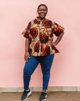 Model wearing beige shirt with brown and orange circles and lines.