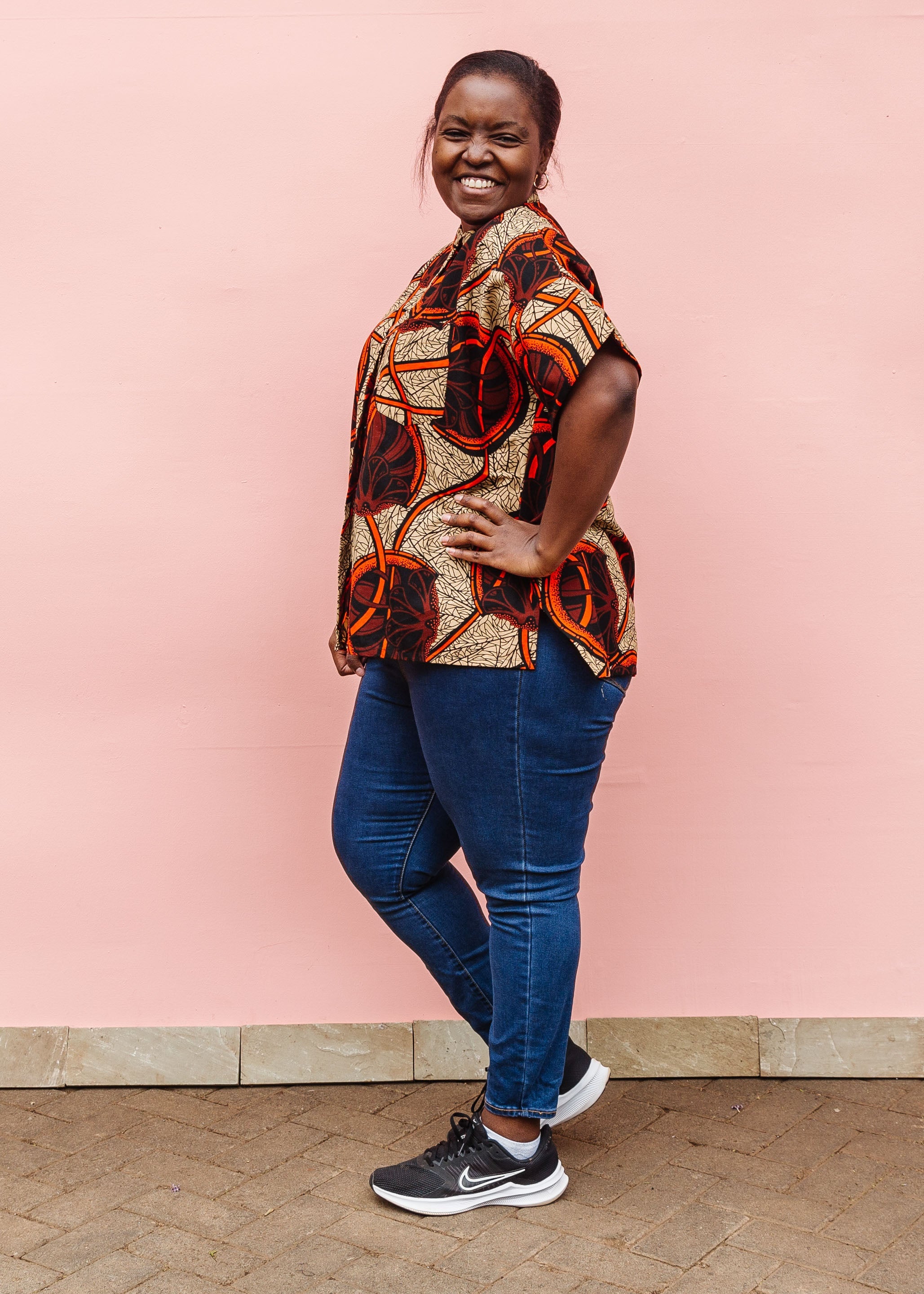Model wearing beige shirt with brown and orange circles and lines.