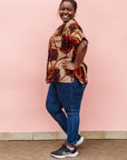 Model wearing beige shirt with brown and orange circles and lines.