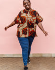 Model wearing beige shirt with brown and orange circles and lines.