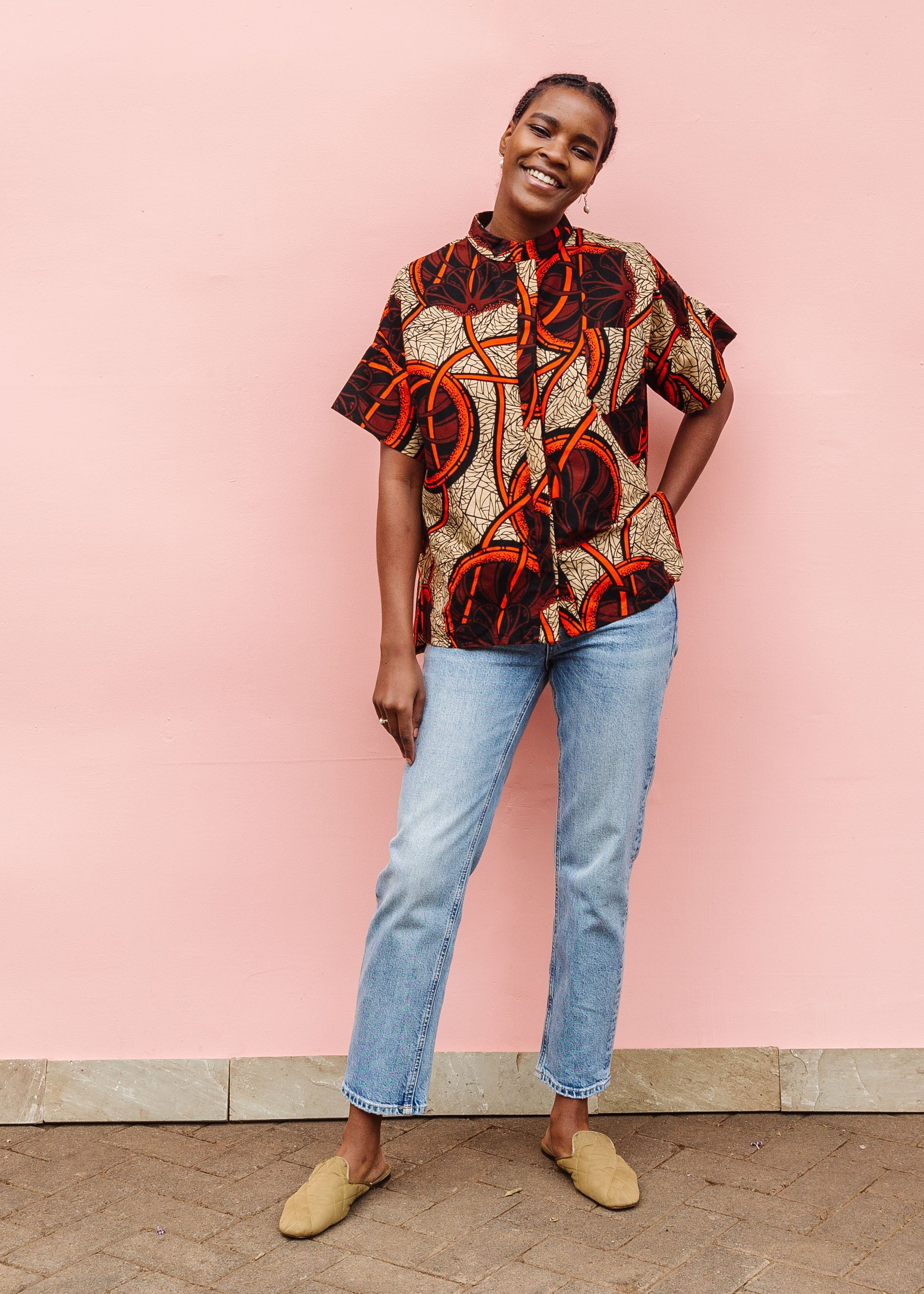 Model wearing beige shirt with brown and orange circles and lines.