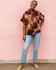 Model wearing beige shirt with brown and orange circles and lines.