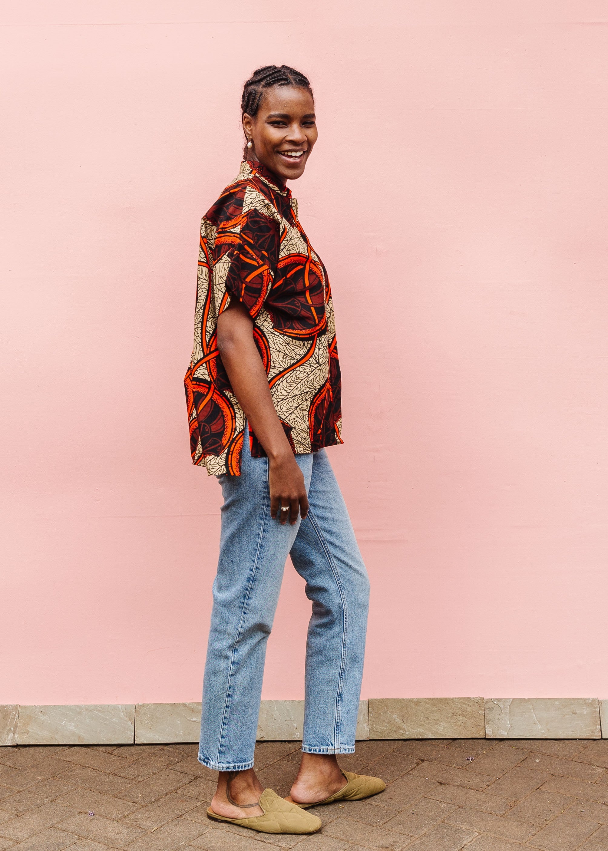 Model wearing beige shirt with brown and orange circles and lines.