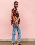 Model wearing beige shirt with brown and orange circles and lines.