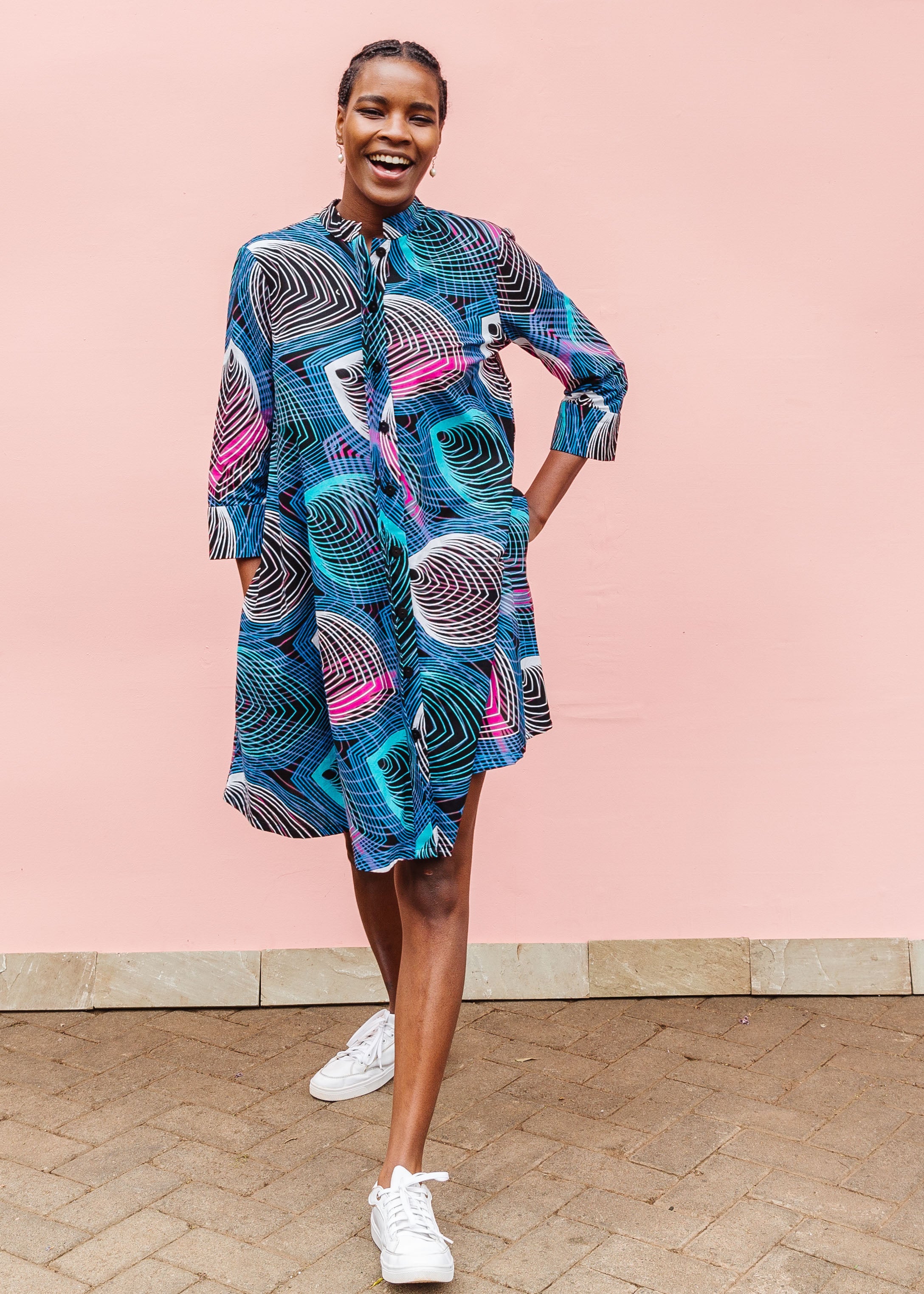 Model wearing black dress with colorful peacock print.