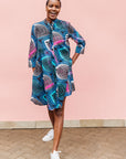 Model wearing black dress with colorful peacock print.
