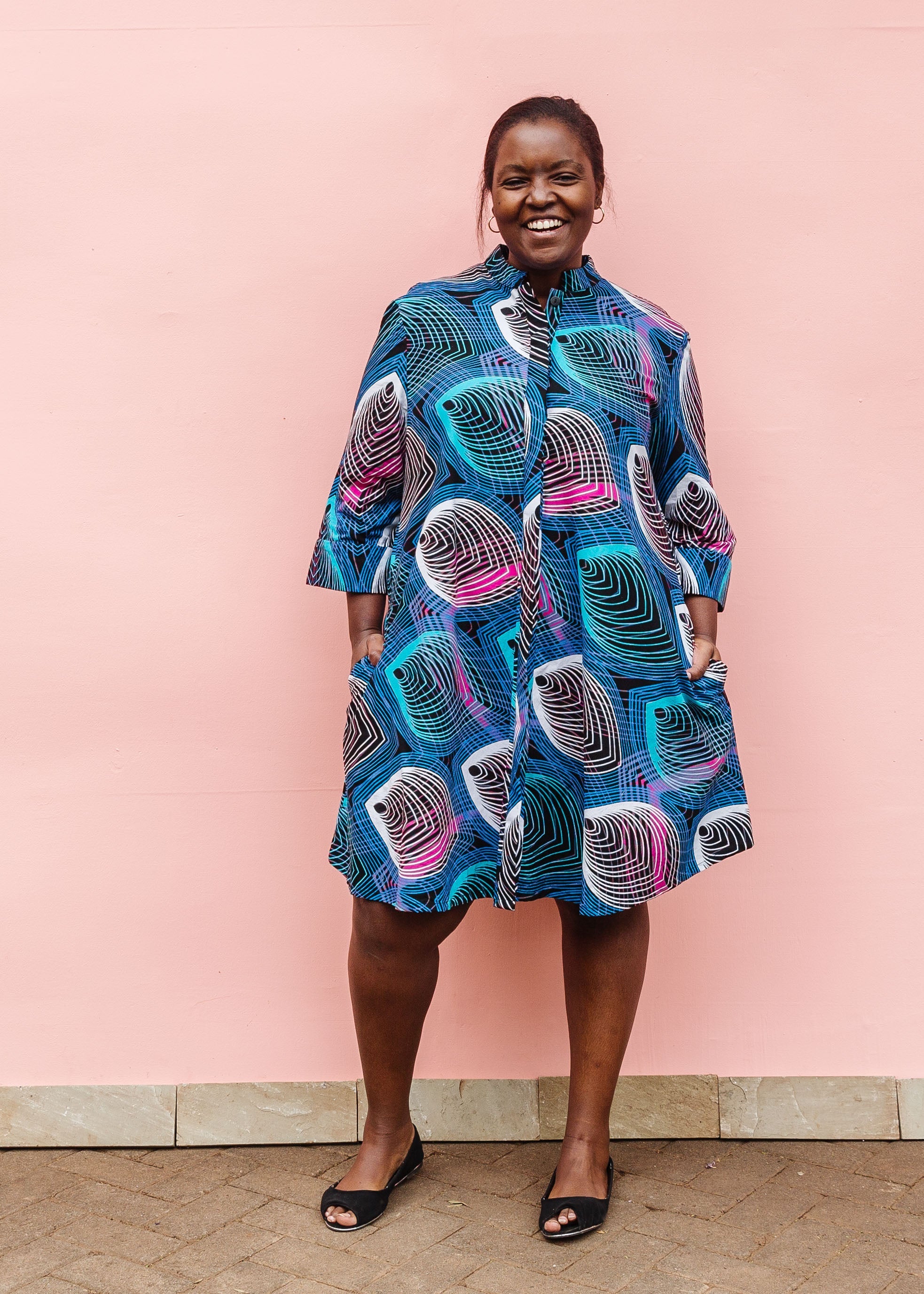Model wearing black dress with colorful peacock print.