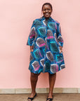 Model wearing black dress with colorful peacock print.