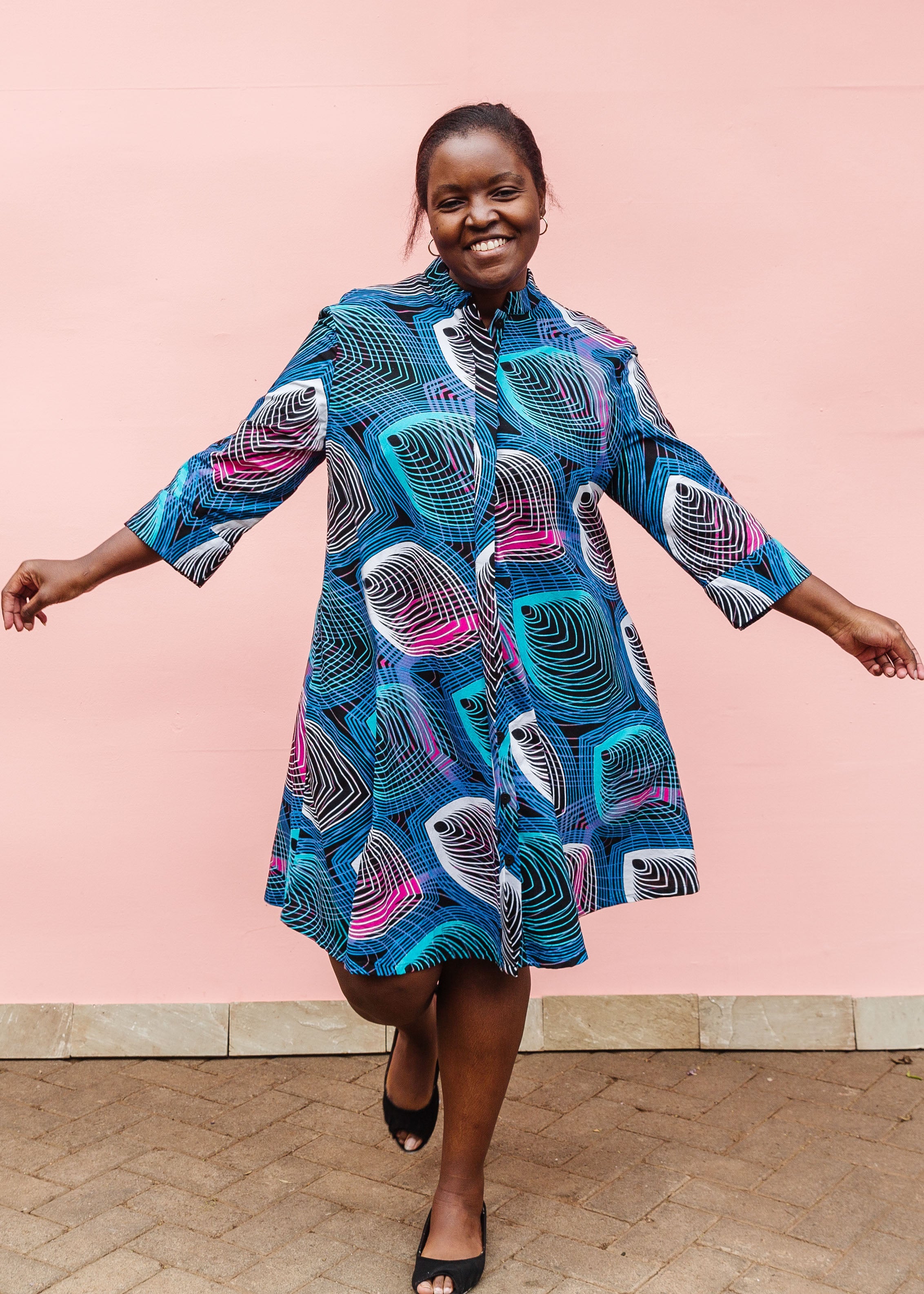 Model wearing black dress with colorful peacock print.