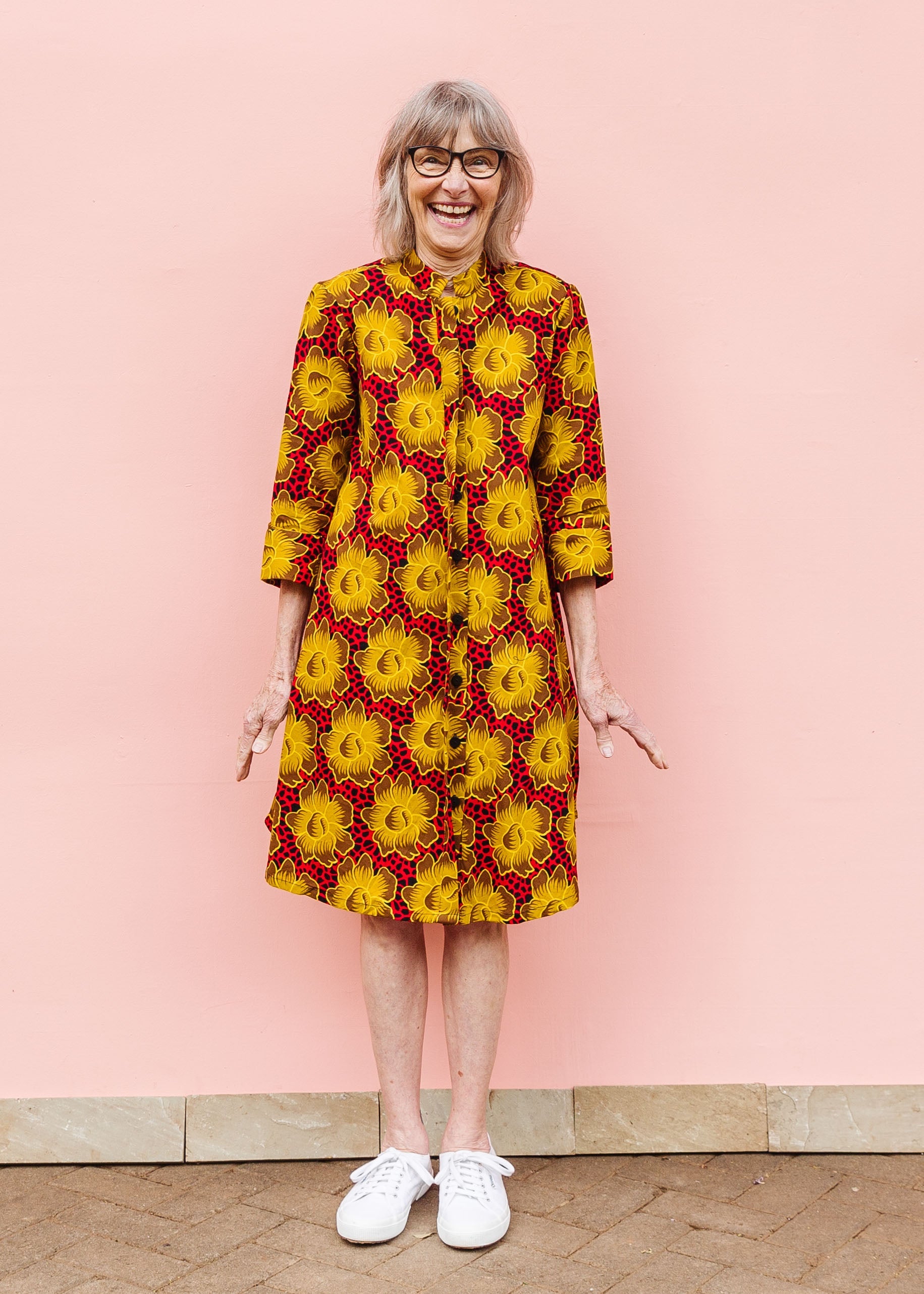 Model wearing red dress with yellow and brown flowers.