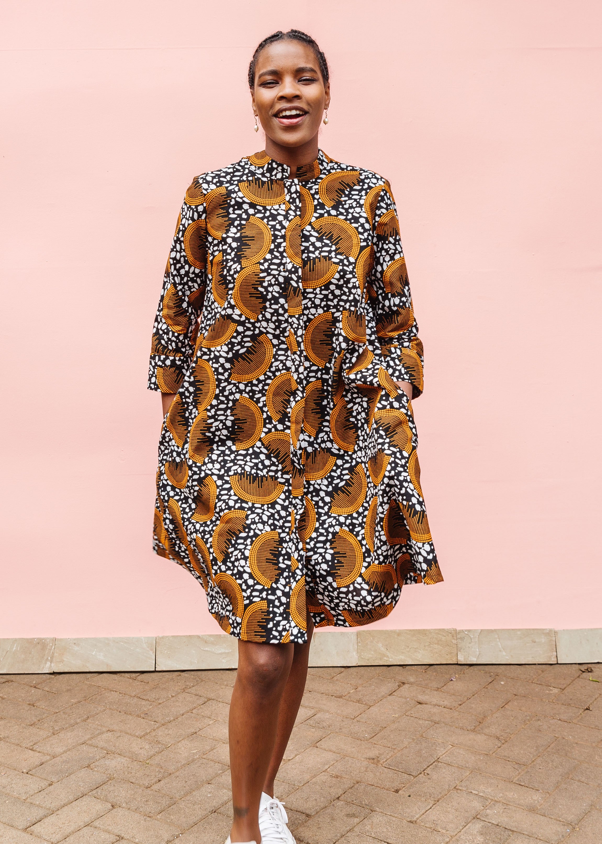 Model wearing black and white dress with orange half circle print.