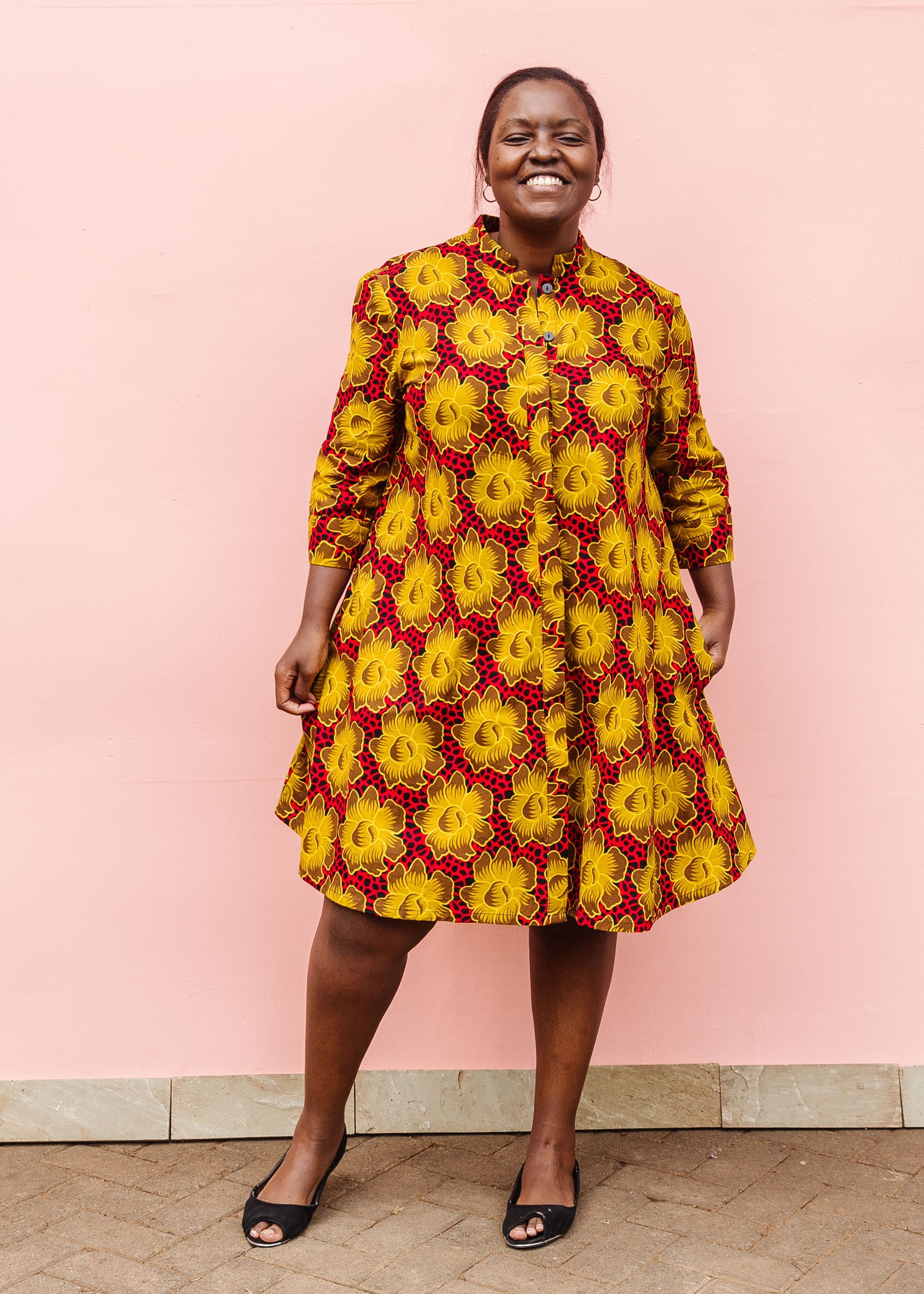 Model wearing red dress with yellow and brown flowers.