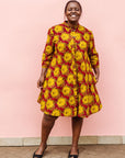 Model wearing red dress with yellow and brown flowers.