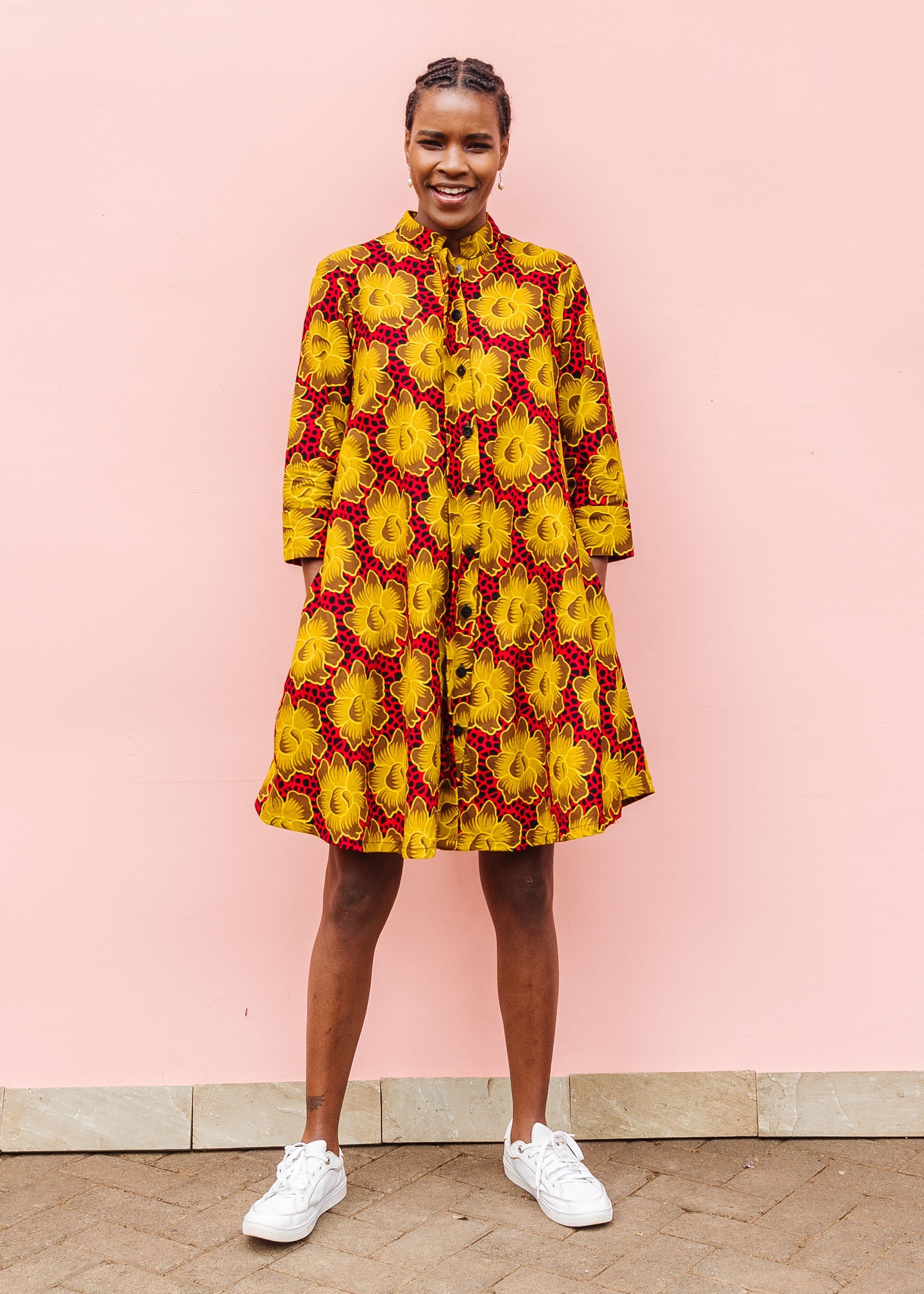 Model wearing red dress with yellow and brown flowers.