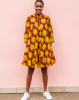 Model wearing red dress with yellow and brown flowers.