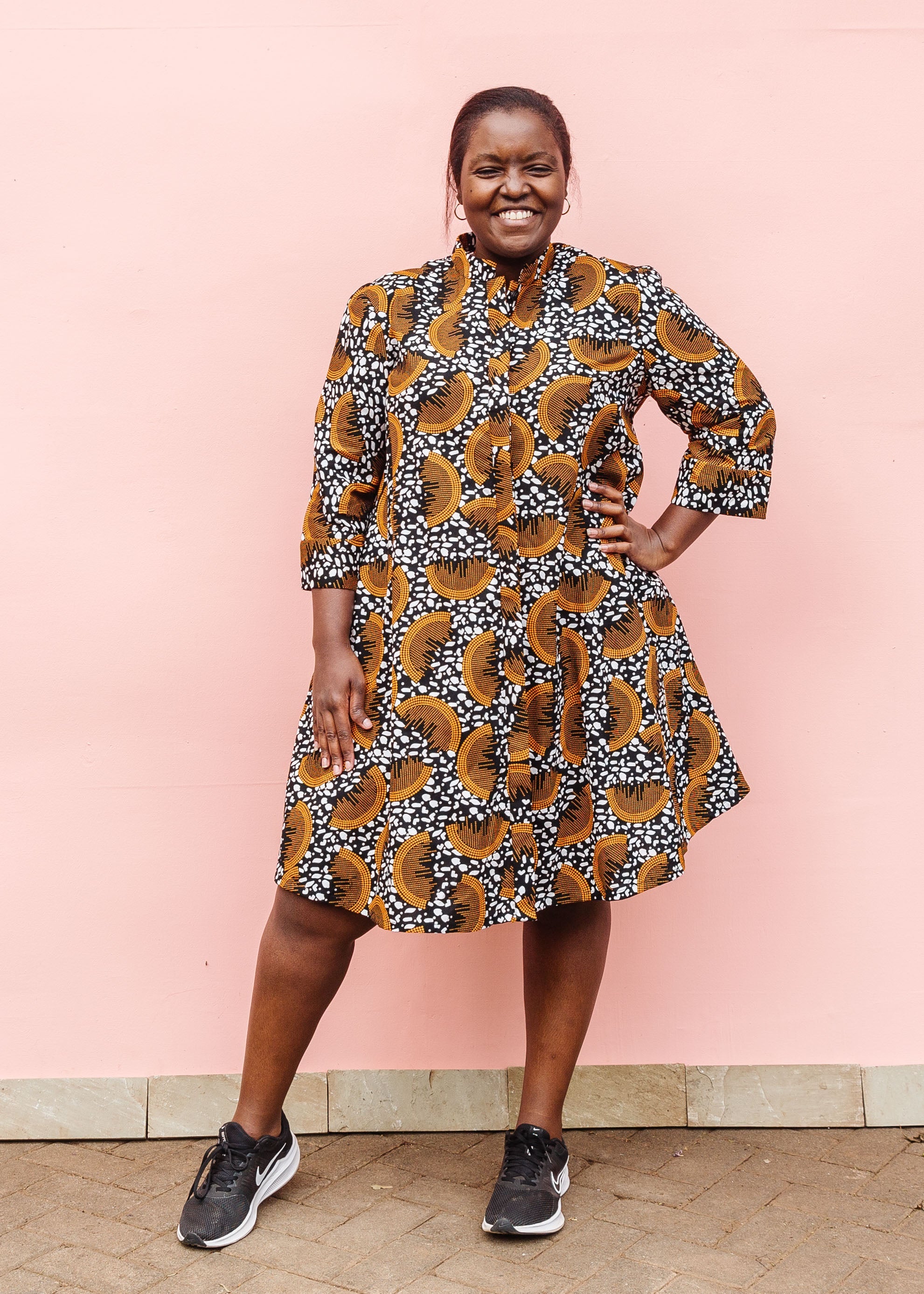 Model wearing black and white dress with orange half circle print.