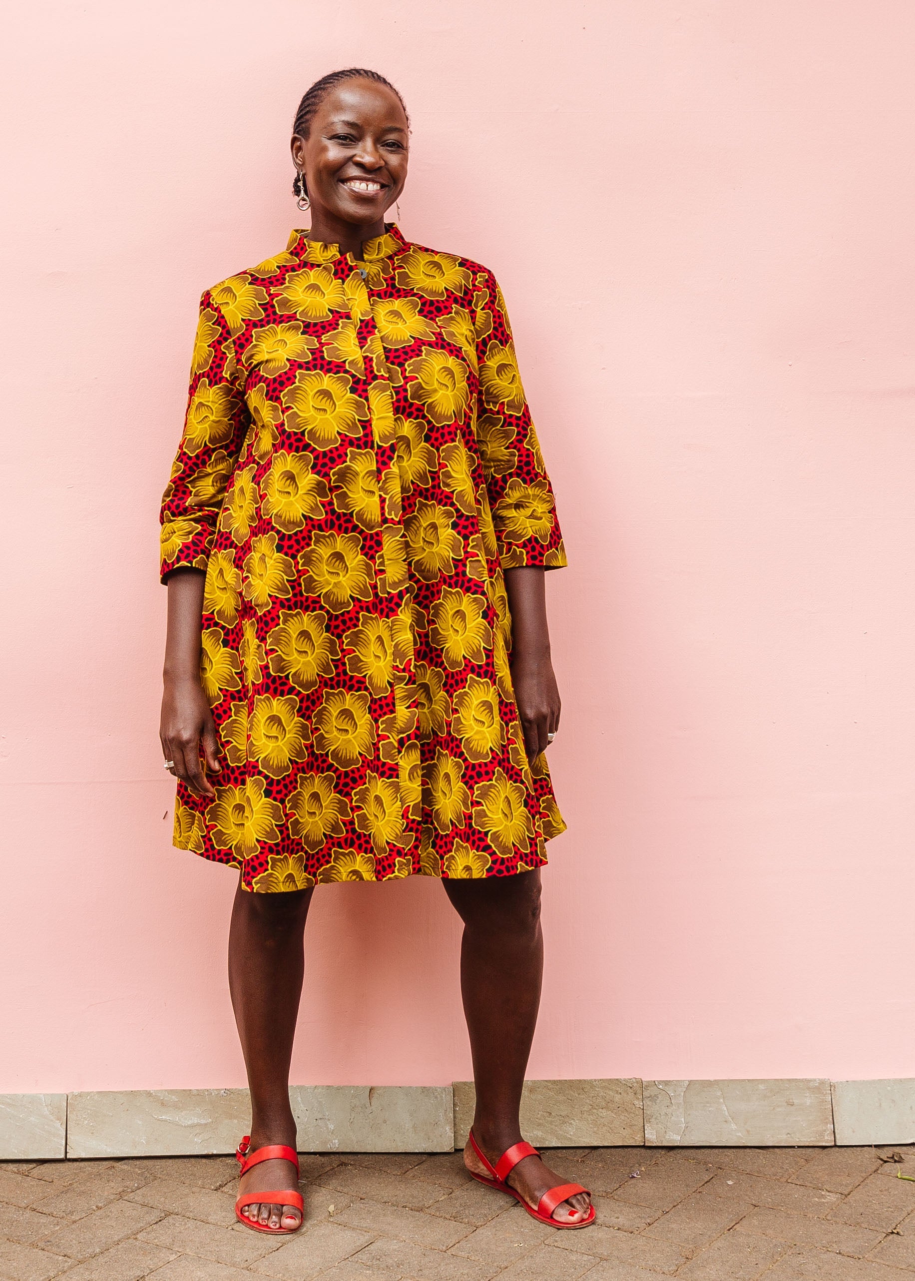 Model wearing red dress with yellow and brown flowers.