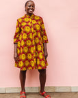 Model wearing red dress with yellow and brown flowers.