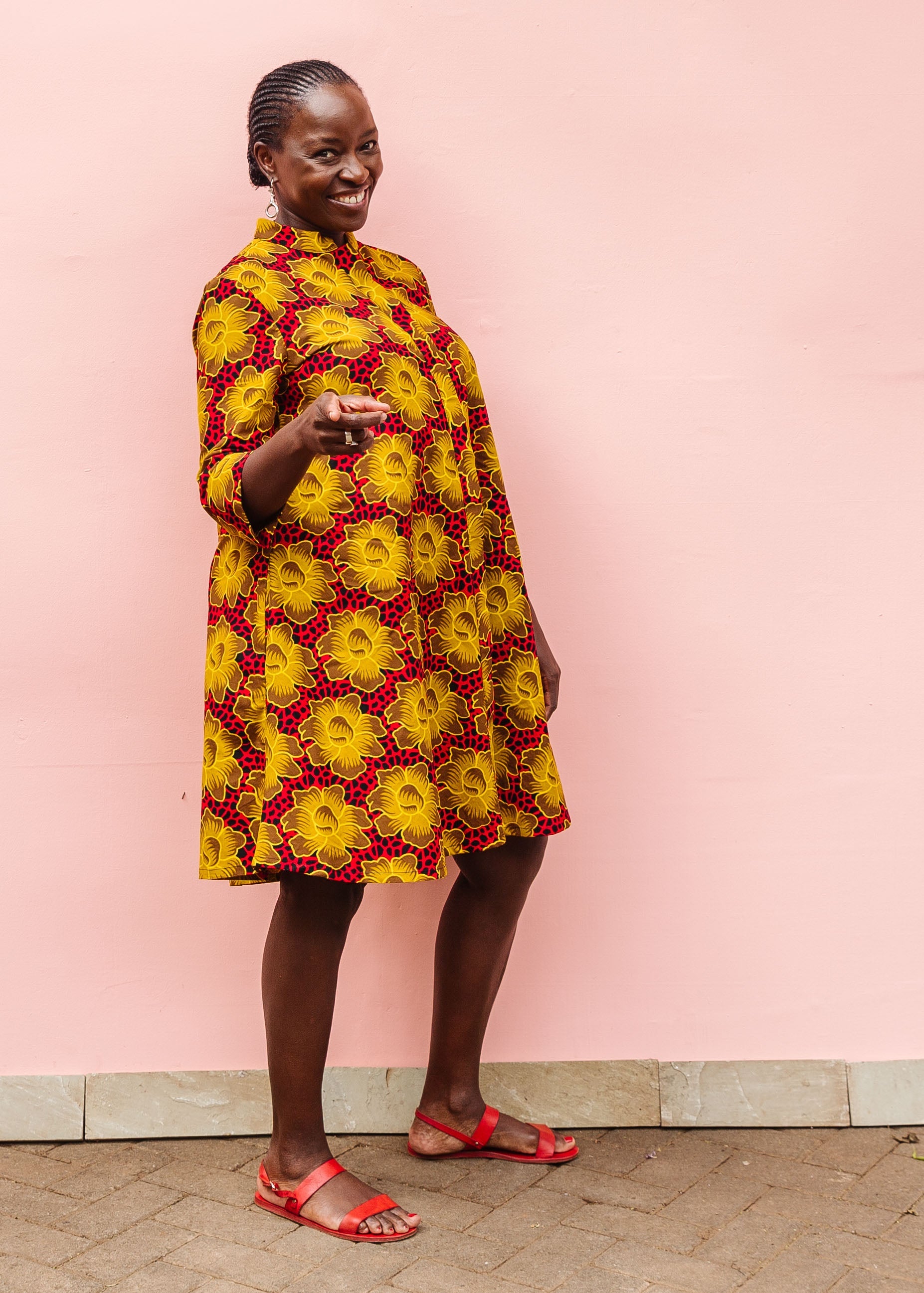 Model wearing red dress with yellow and brown flowers.