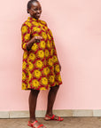 Model wearing red dress with yellow and brown flowers.