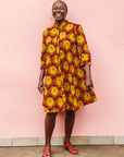 Model wearing red dress with yellow and brown flowers.
